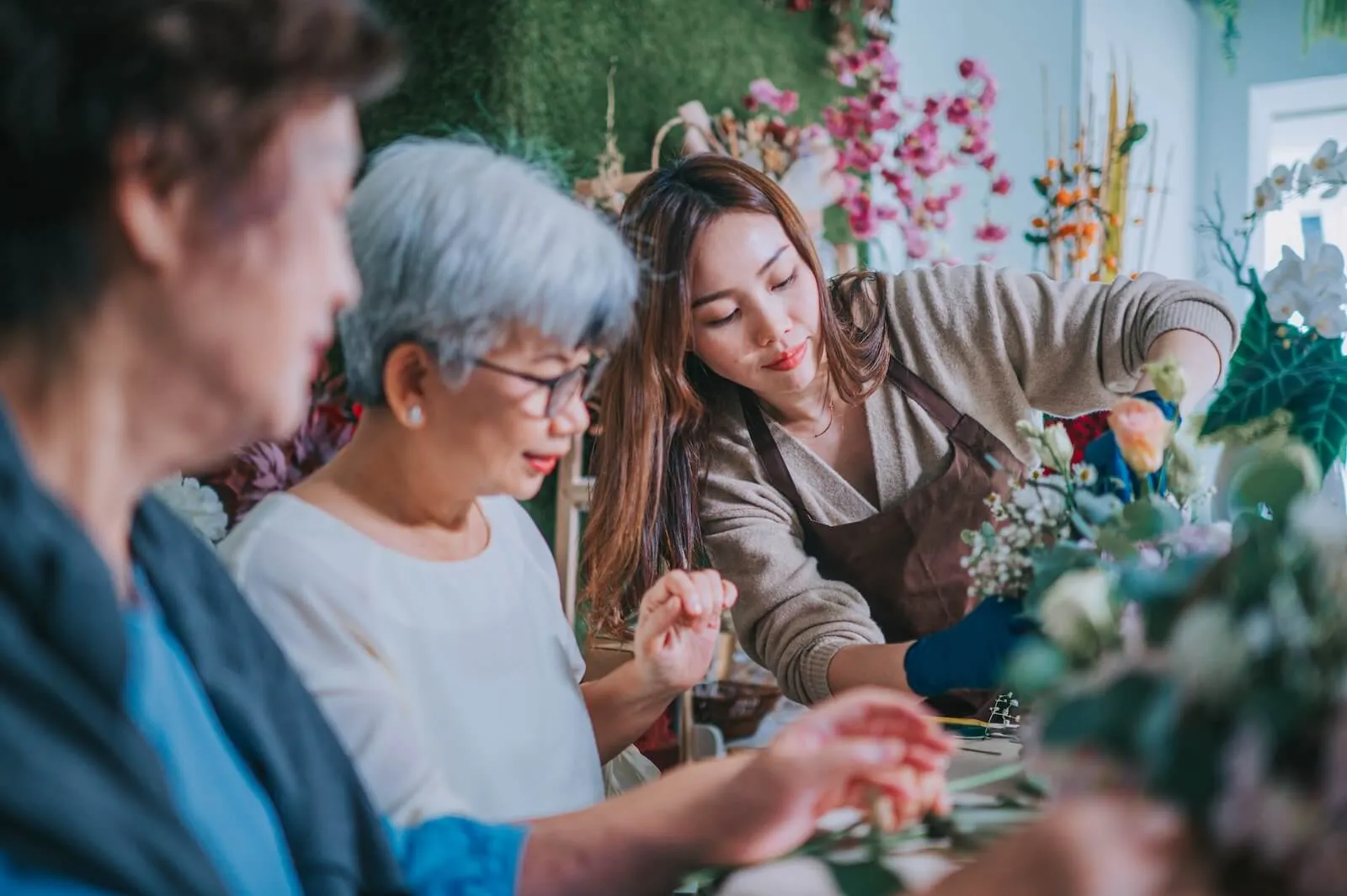 attending a floral jamming workshop, making a flower bouquet assisting by an experienced florist. Small business, art and craft workshop, hobbies concept