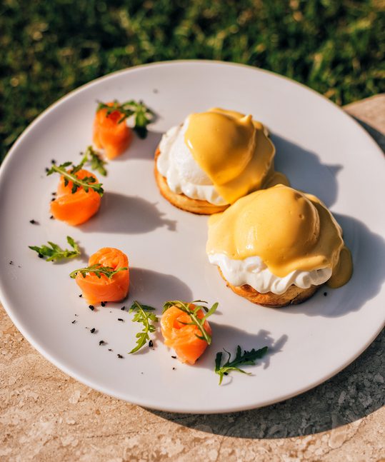 Two poached eggs with egg yolk with salmon on a white plate