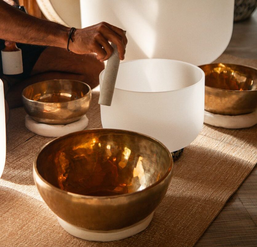Spa therapist playing crystal singing bowls at wellness retreat for sound healing treatment meditation